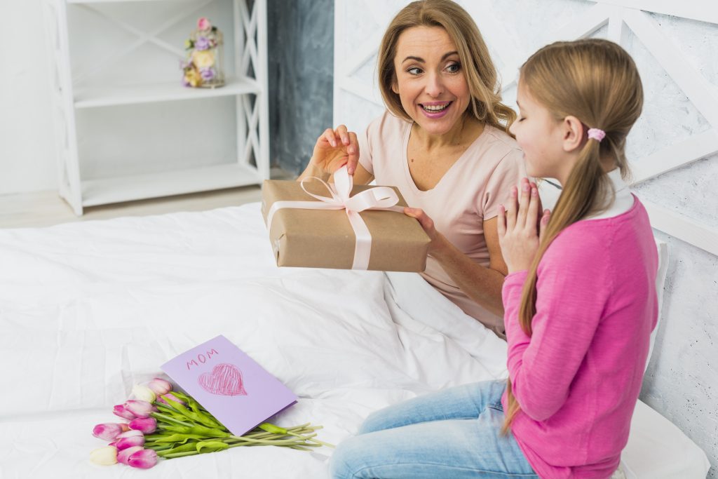 mother-daughter-sitting-bed-with-gift-scaled
