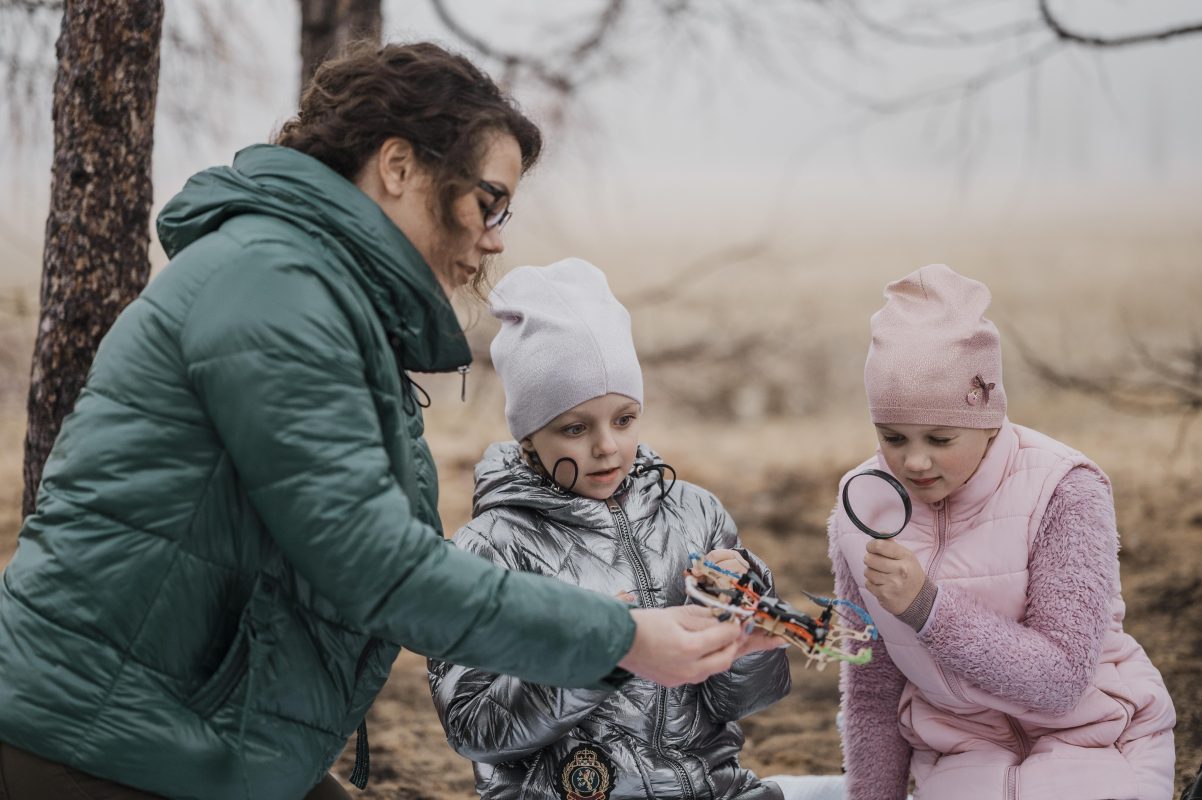 mère et enfants observant un objet lors d’une activité en plein air
