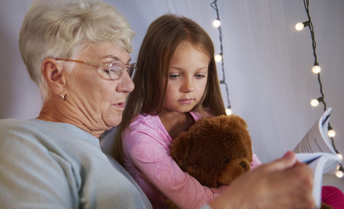 Grand-mère lisant une histoire à sa petite-fille avant le coucher, moment complice en famille