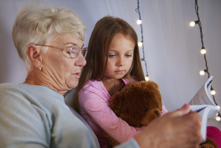 Grand-mère lisant une histoire à sa petite-fille avant le coucher, moment complice en famille