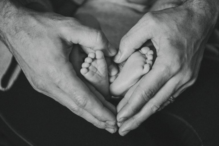 Mains de parents formant un cœur autour des pieds d’un nouveau-né symbolisant l’amour familial