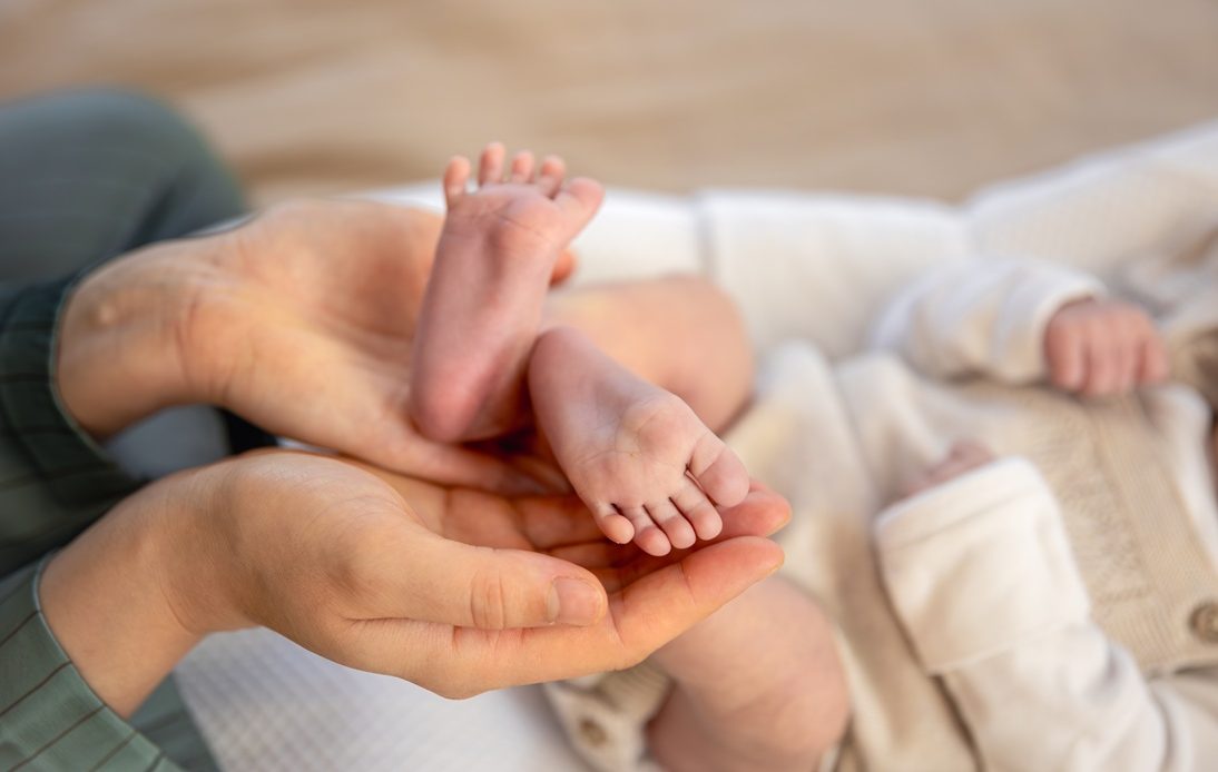 Pieds de nouveau-né tenus délicatement dans les mains d’un parent