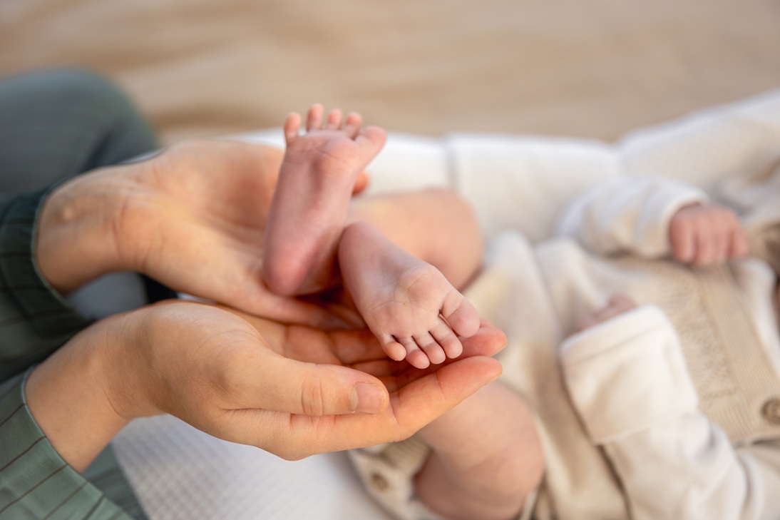 Pieds de nouveau-né tenus délicatement dans les mains d’un parent